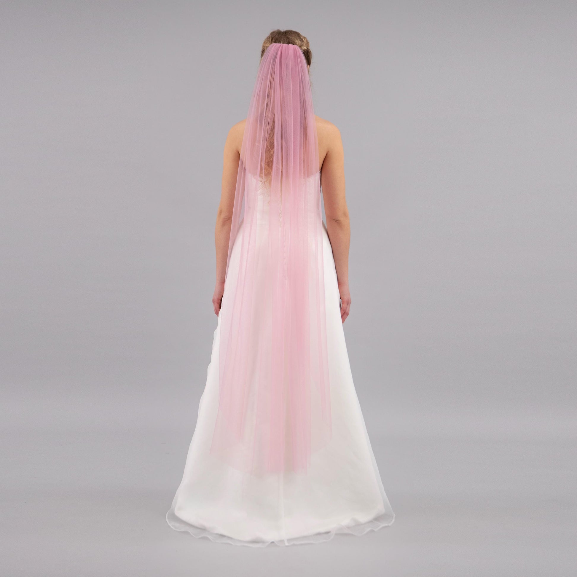 Woman wearing a pink veil on a gray background