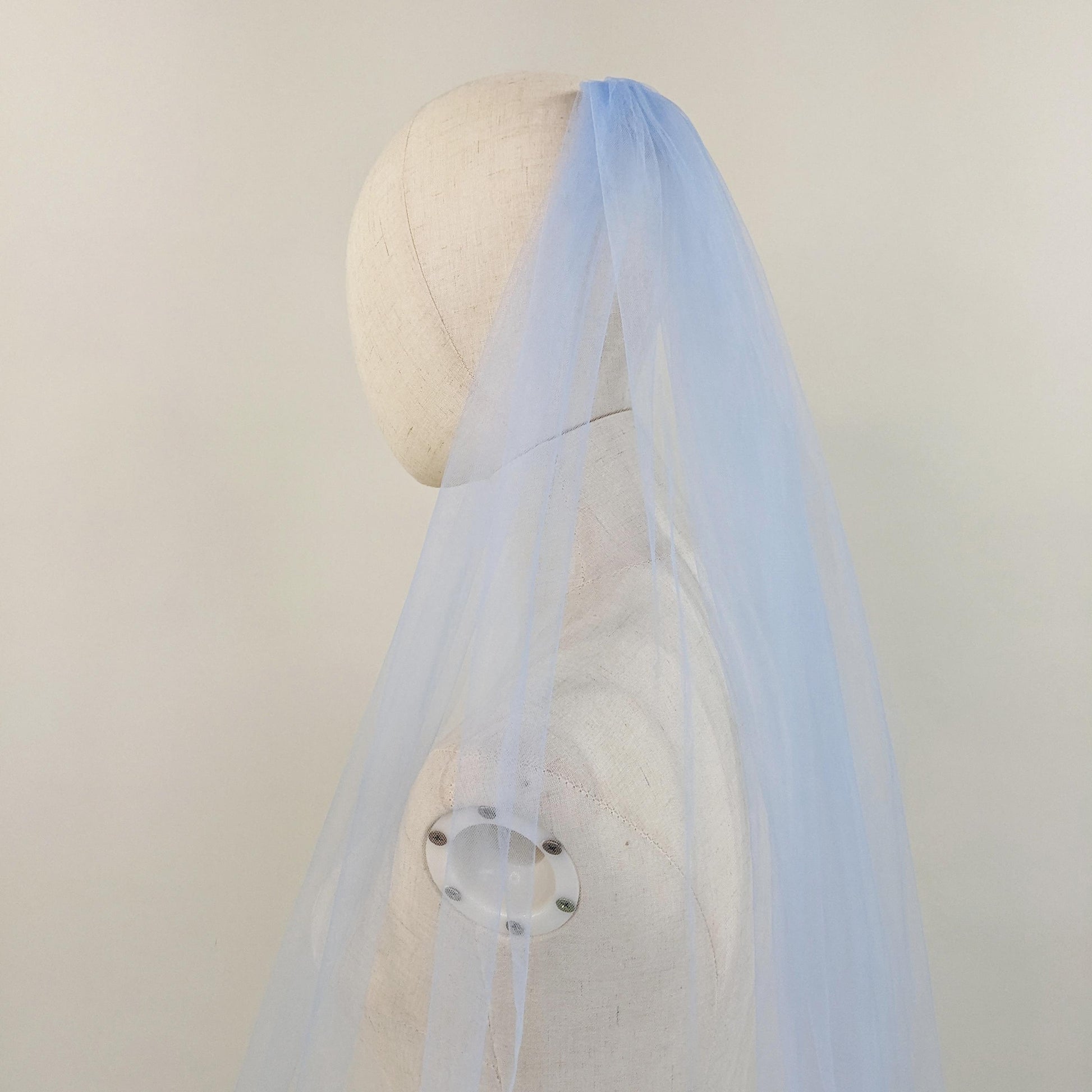 Light blue veil on a mannequin head against a plain background