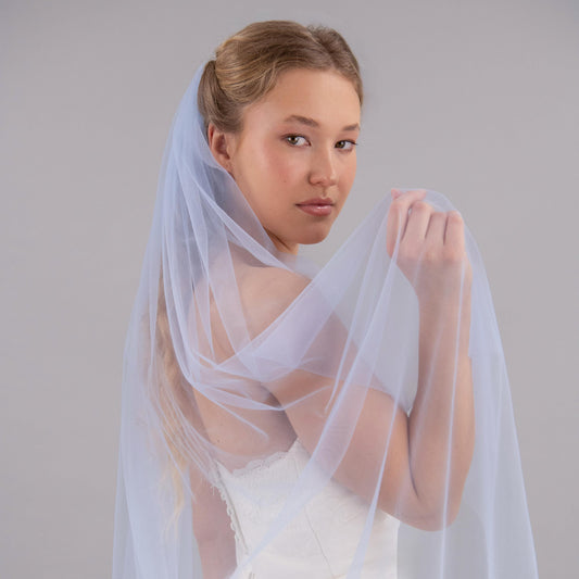 Woman wearing a light blue wedding veil against a gray background