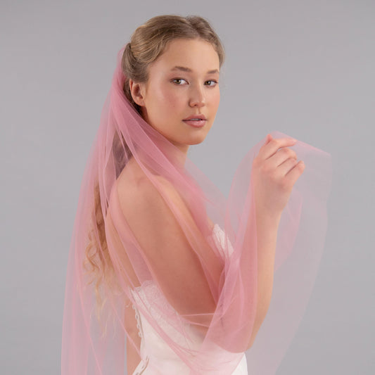 Woman wearing a pink veil against a gray background
