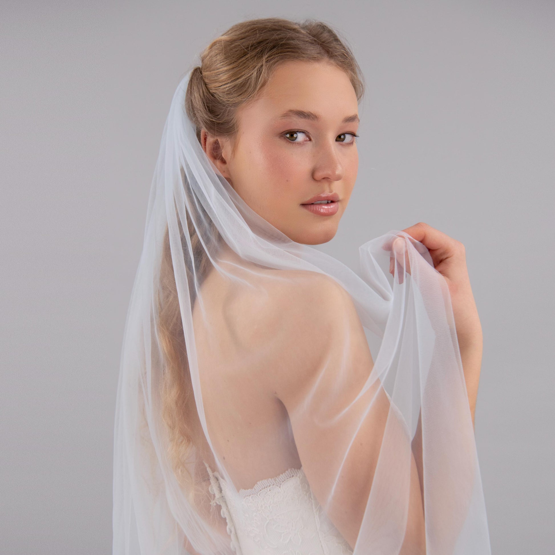 Woman wearing a blue wedding veil against a plain background