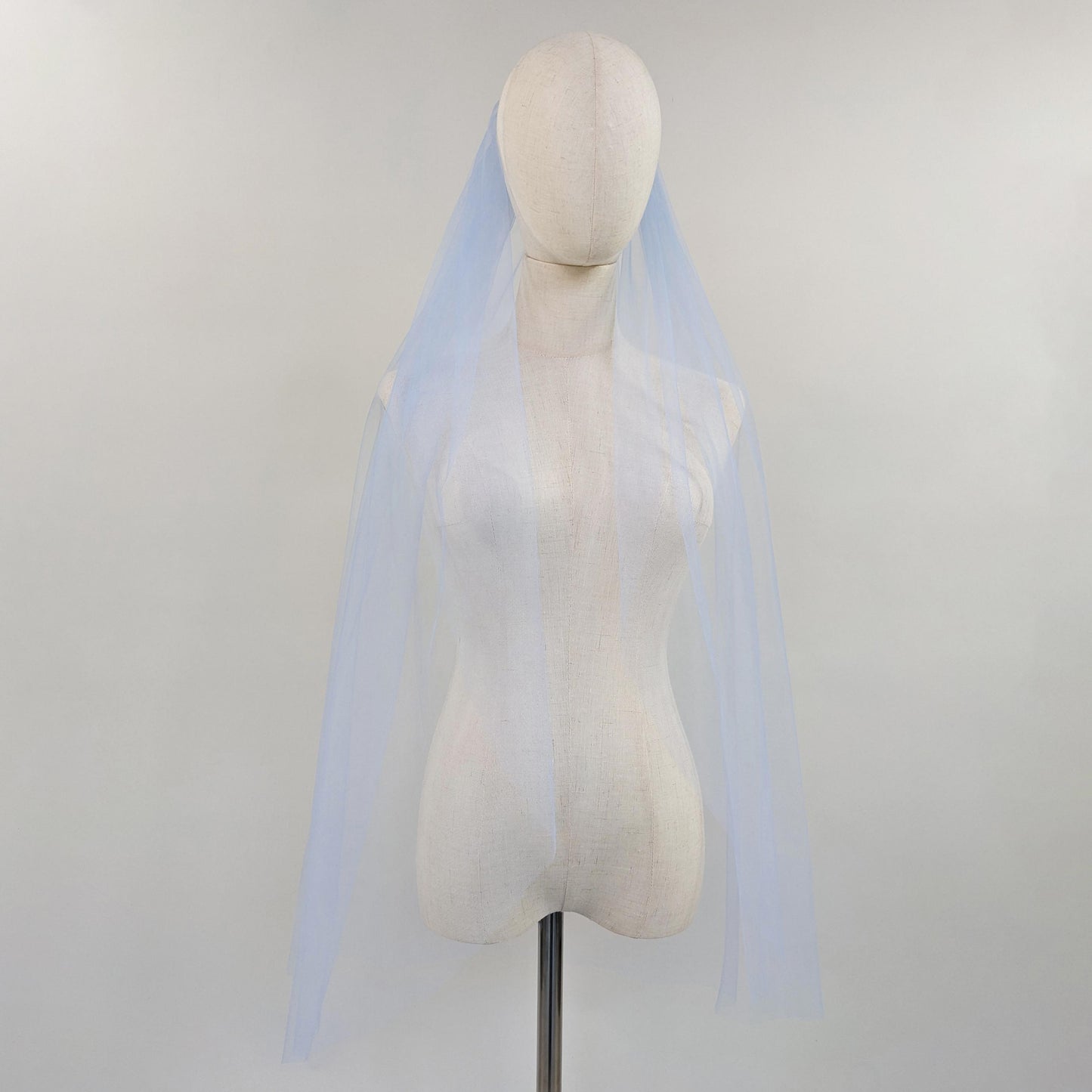 Mannequin wearing a light blue veil against a plain background