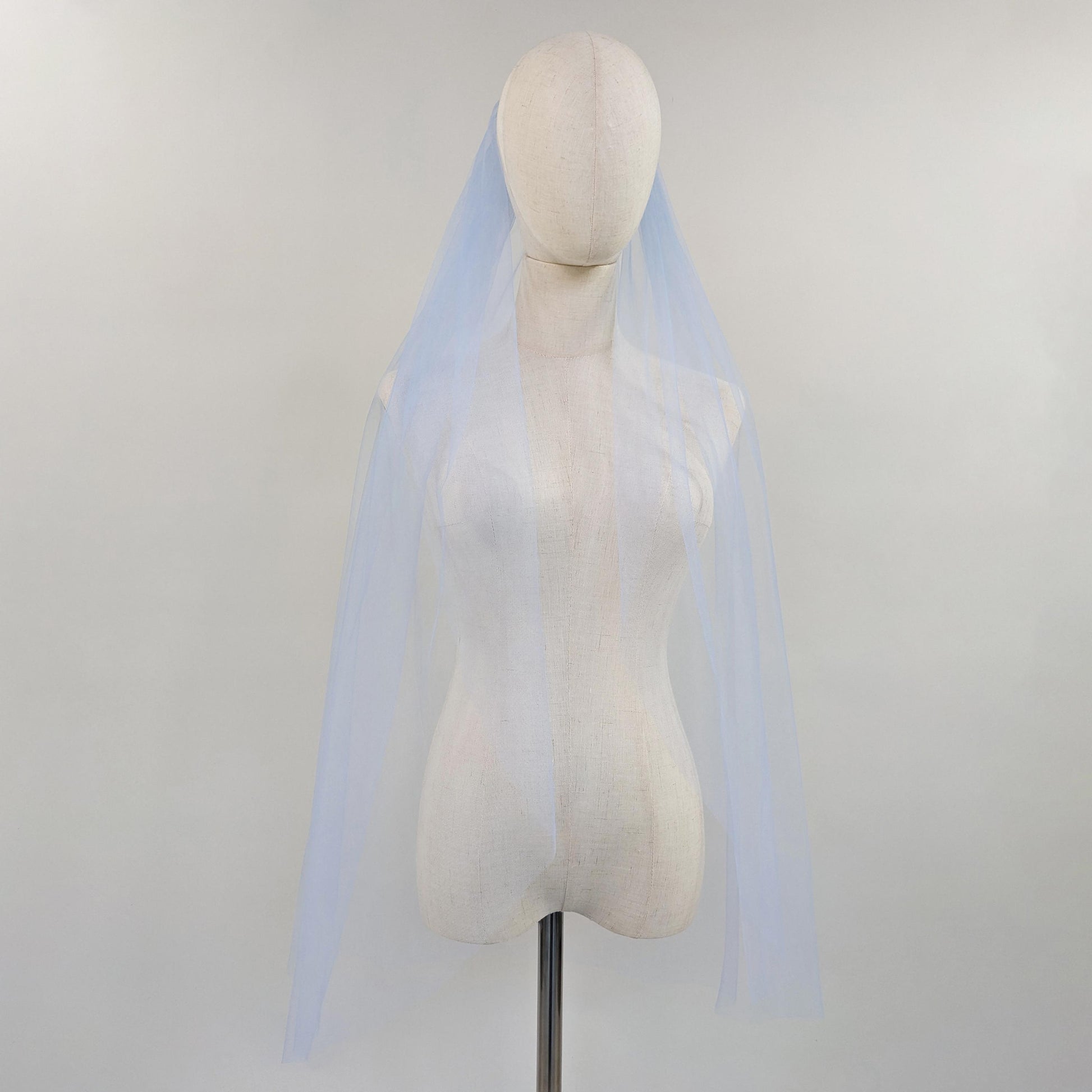 Mannequin wearing a light blue veil against a plain background